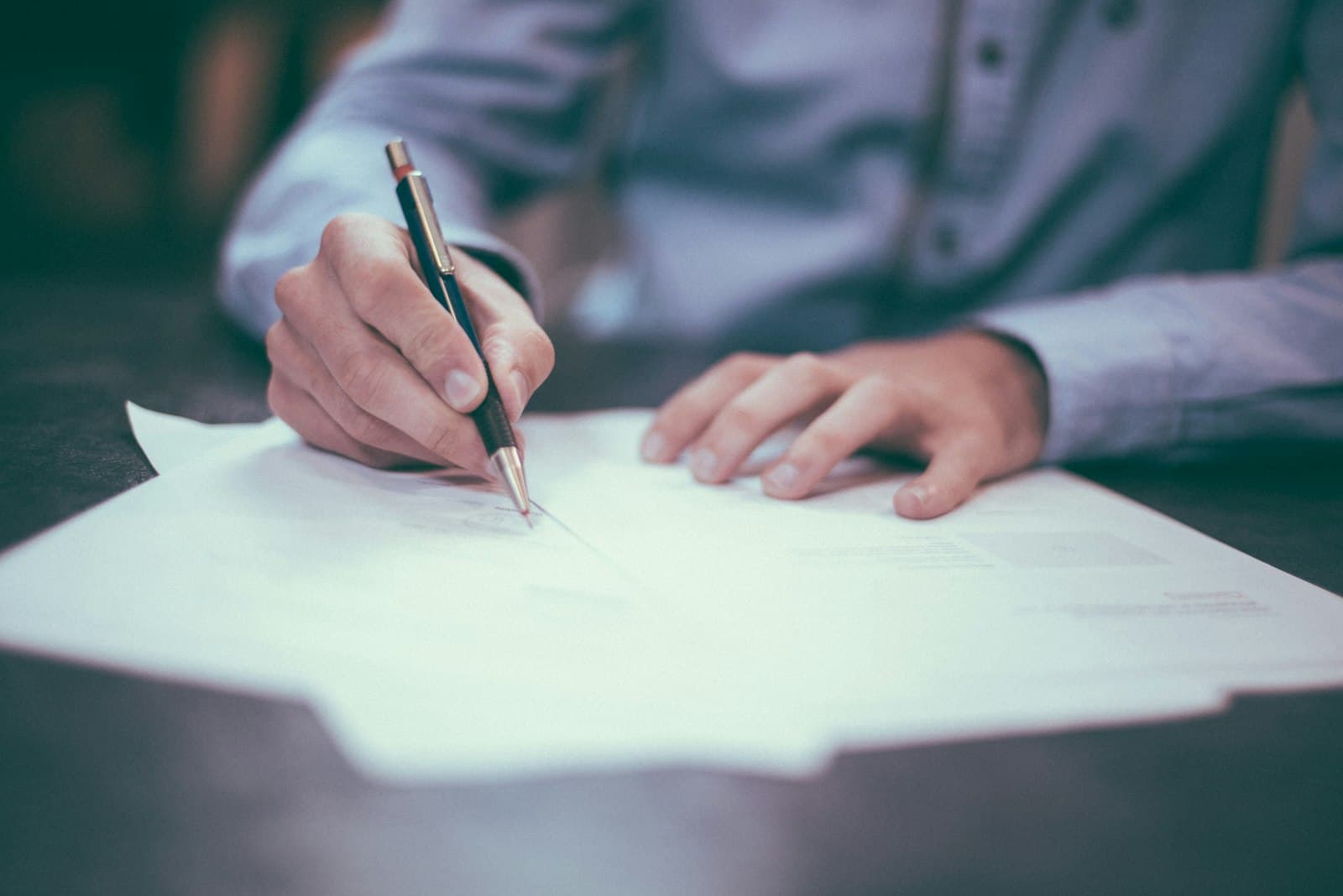 Employer reviewing payroll documents at a desk in natural light (Photo: Unsplash)
