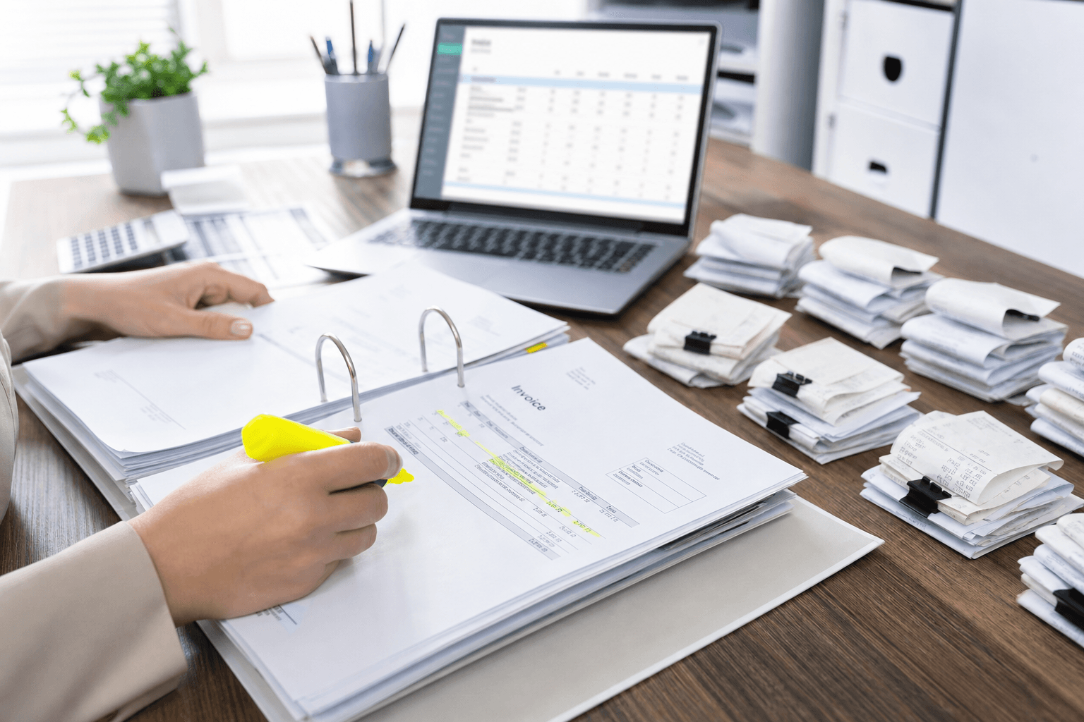 Organized bookkeeping desk with ledger binder, invoices, receipts and accounting laptop