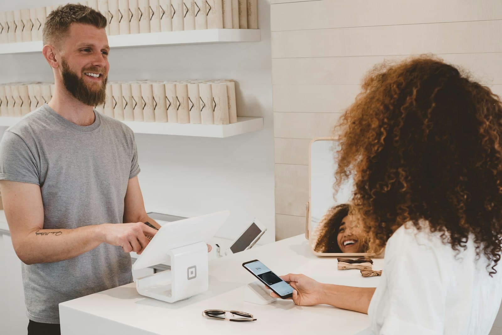 Small business owner at a shop counter with a customer, natural light and a working retail workspace (Photo: Unsplash)