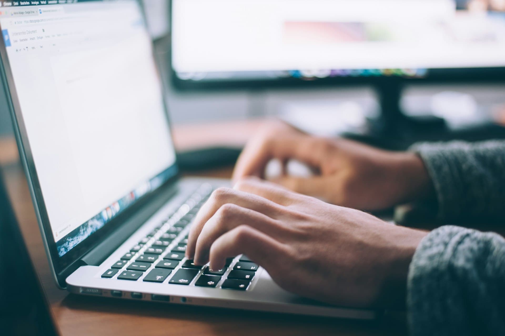 Business owner typing on a laptop at a wooden desk in natural light (Photo: Unsplash)