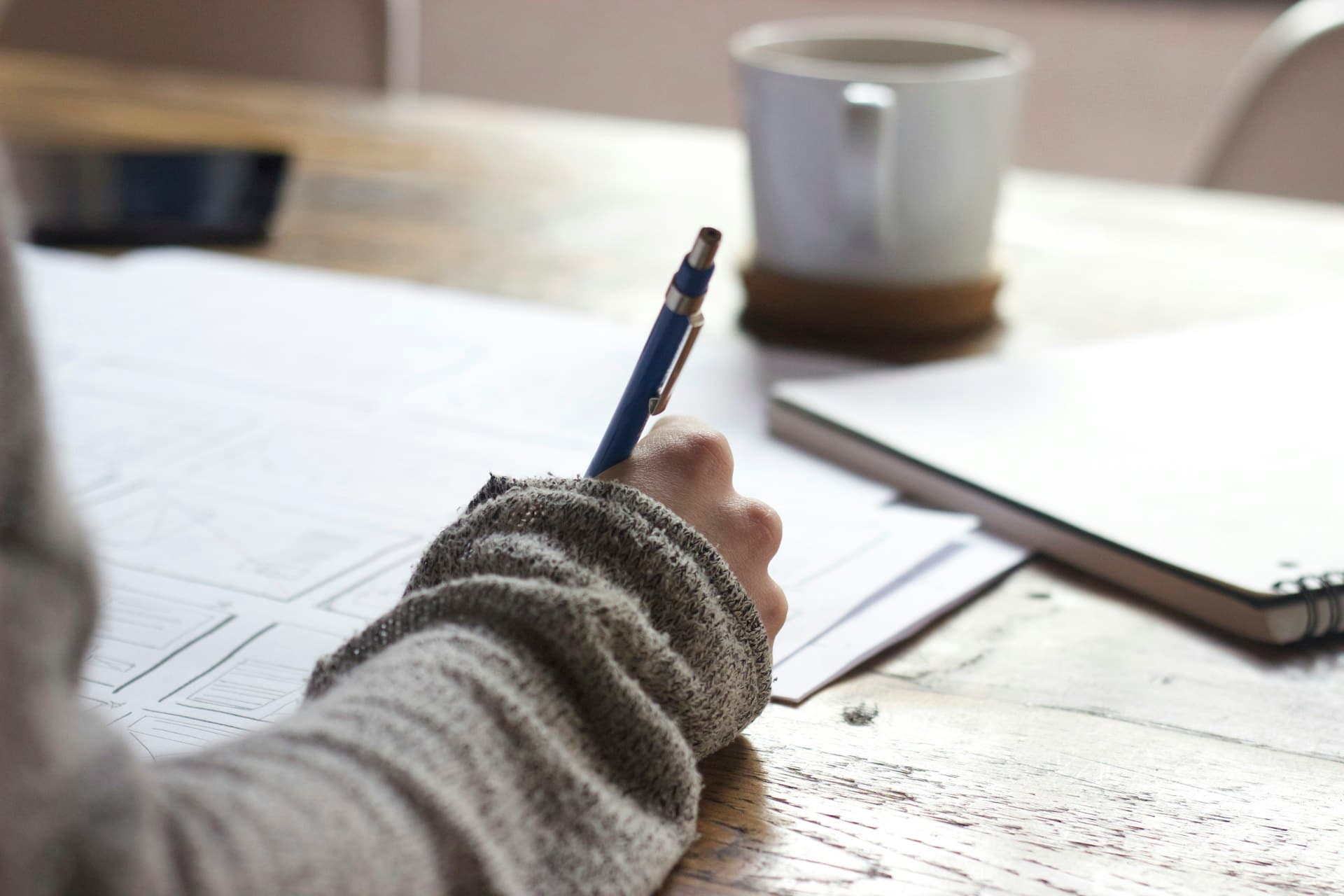 Person reviewing financial documents at a wooden desk in natural light (Photo: Unsplash)